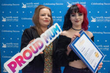 two women smiling - they are standing in front of signs with NWRC on them and have a sign that says proud mum