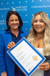 two women smile holding a certificate