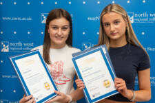 two students hold certificates with branding behind them
