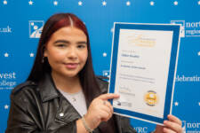 student holds a certificate with branding behind them