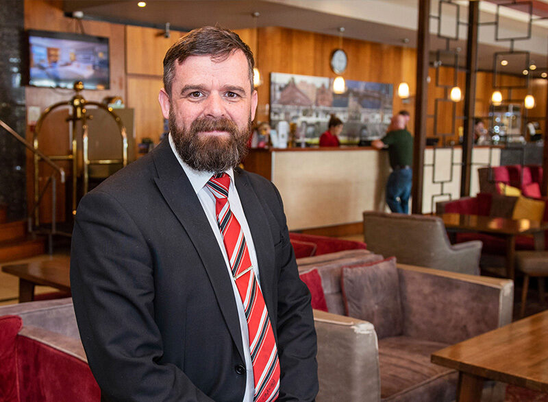 Mature male manager wearing a suit with red tie in hotel lobby