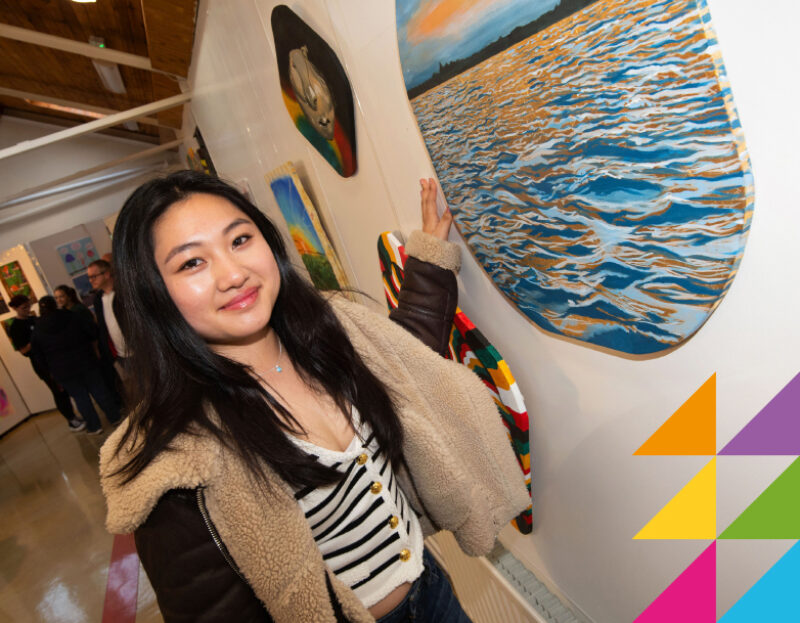 Young chinese female smiling while presenting her artwork at college art show