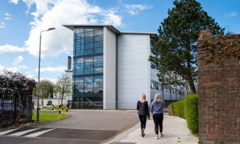 NWRC Limavady exterior campus with two female walking towards the main building with trees in foreground