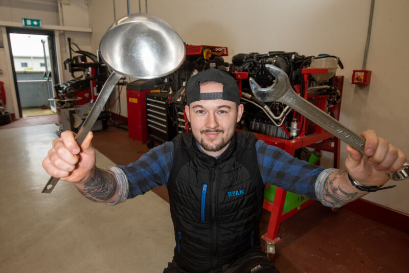 man in garage holding a ladle and spanner