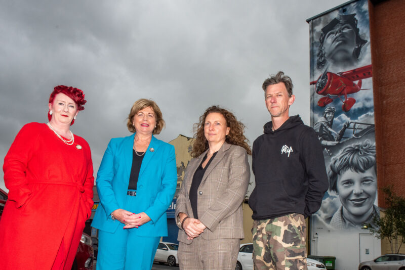 Three women and a man pictured at the Amelia Earhart mural