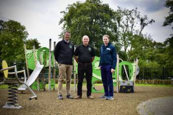 Three men standing in a children's playground