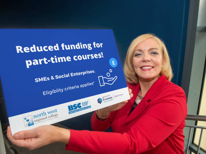 Businesswoman in  a red suit holds up a rectangular graphic for reduced funding for part time courses.